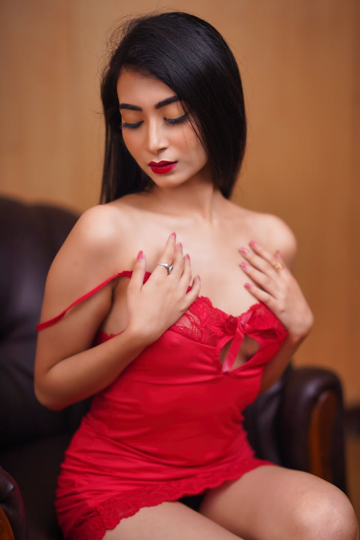 Young woman in seductive red lingerie posing elegantly indoors, showcasing beauty and fashion.