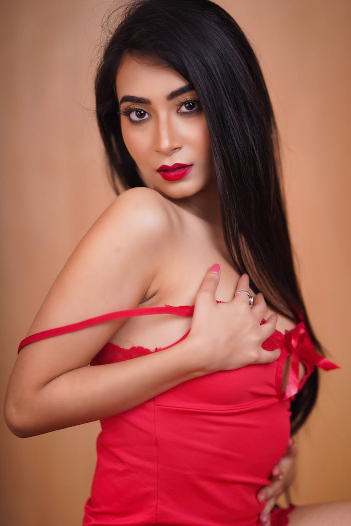Sensual portrait of an adult woman posing in red lingerie with alluring red lips.